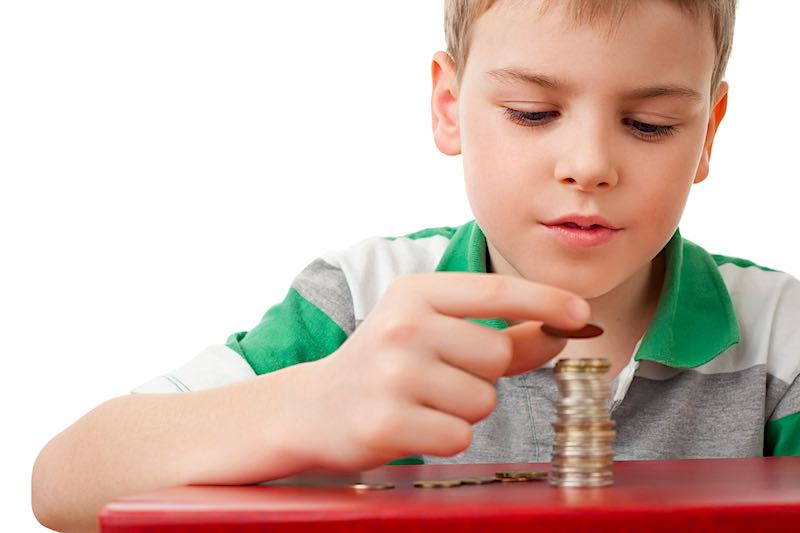 A boy stacking coins that he is saving for the future.