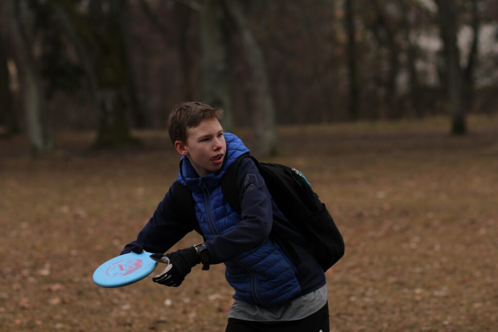 A boy playing frisbee golf. Disc golf is a very cheap sport to get started playing.