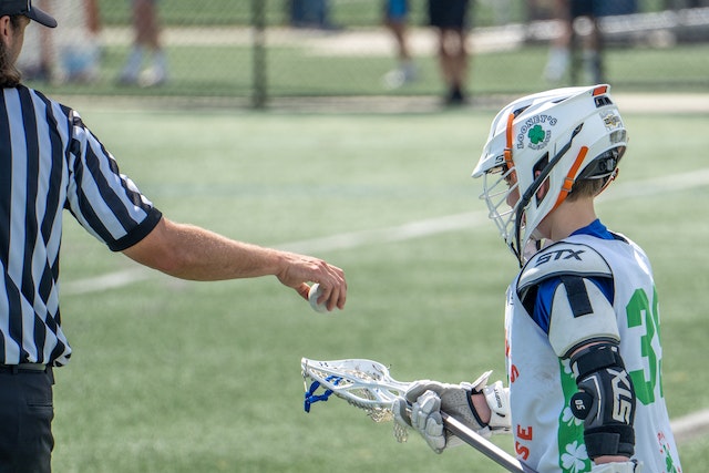referee giving lacrosse kid the lacrosse ball.