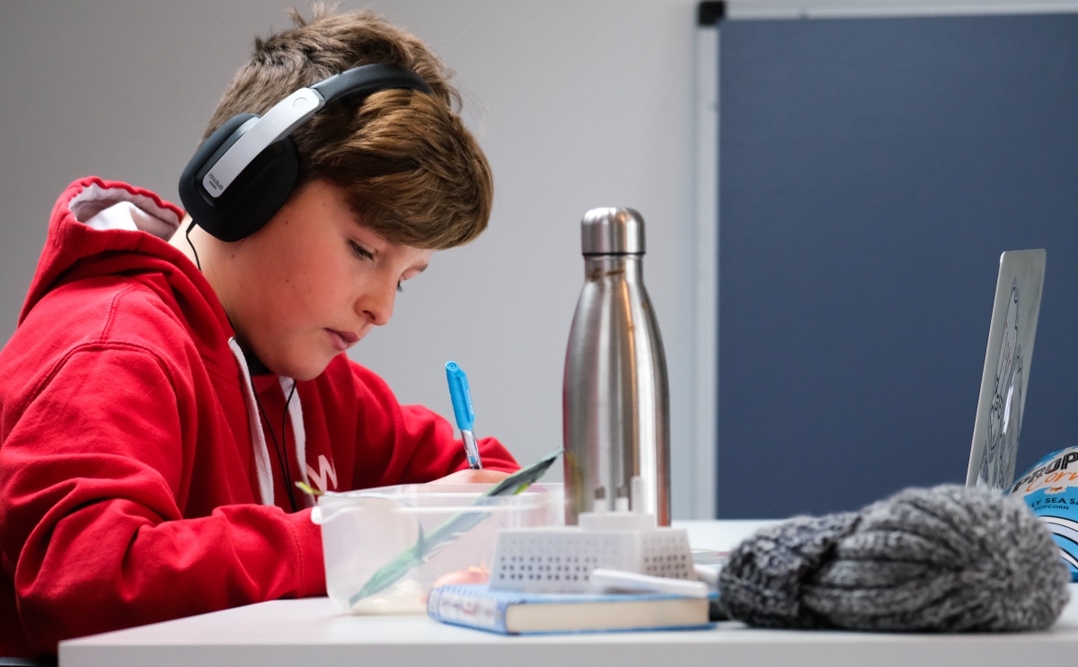 kid working on desk with water bottle and computer.