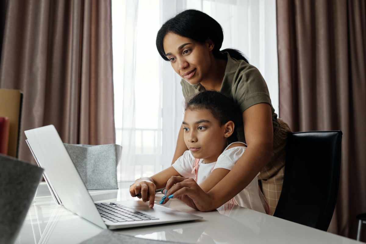 Mother helping child with computer school homework.