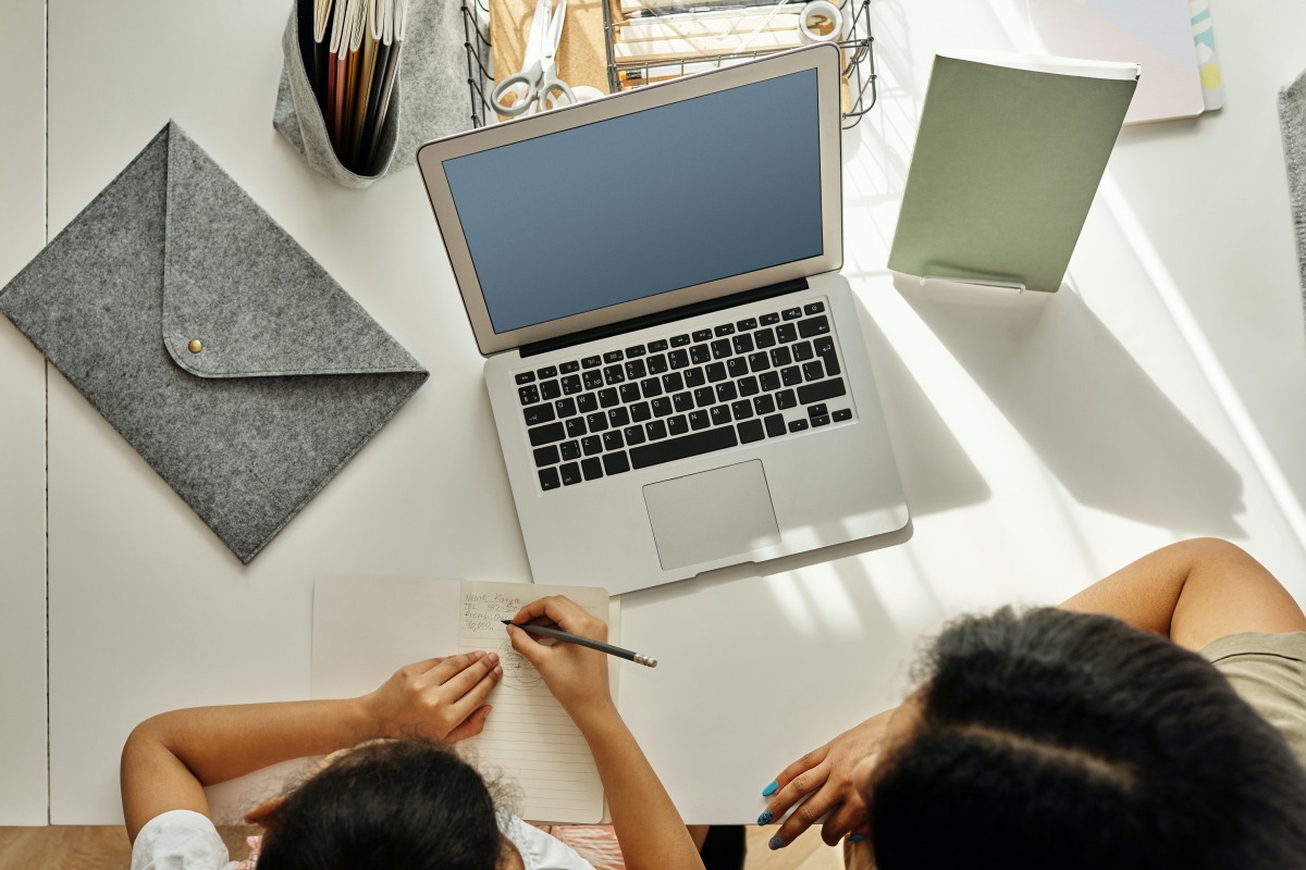 Overhead Shot of Child Getting help from Parent with homework. Computer and notepad. Should parents help children with homework?