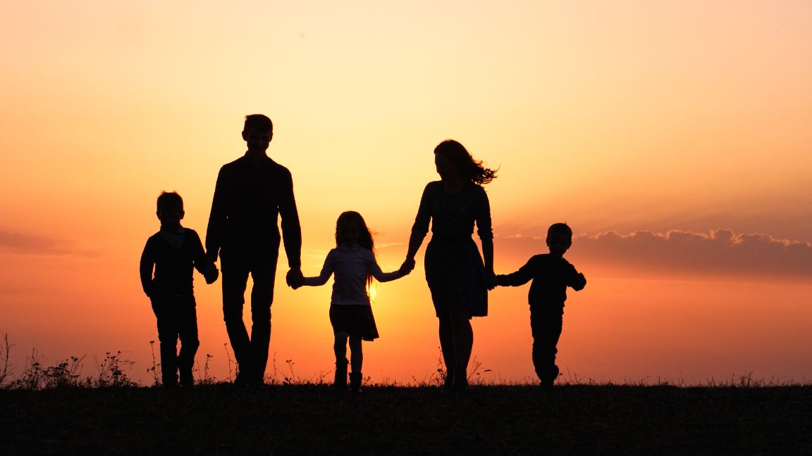 Family holding hands walking into the sunset. Making New Years Family Goals.