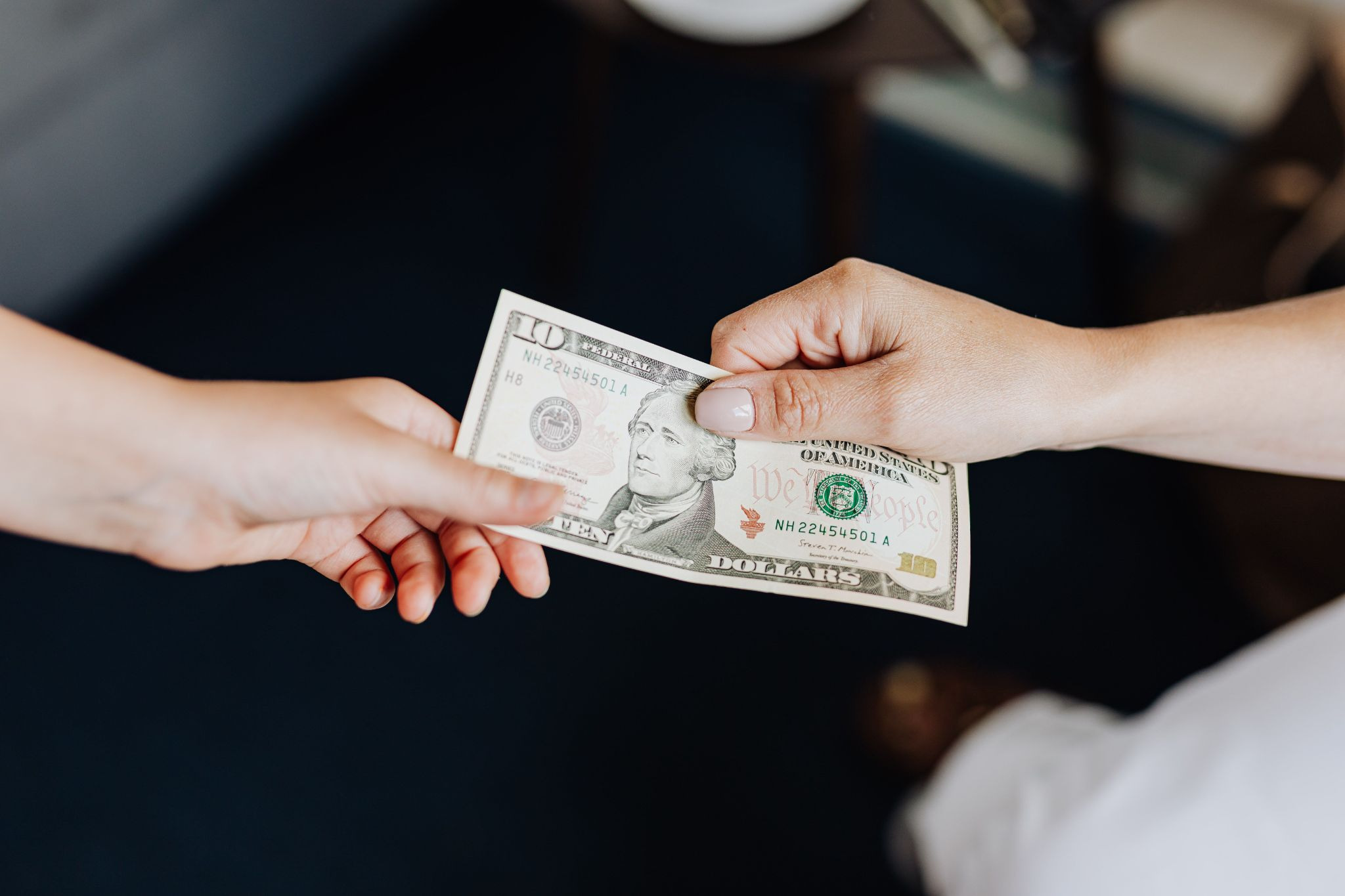 2 hands exchanging a ten dollar bill