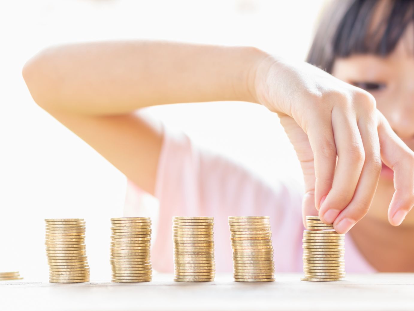 Child stacking coins indicating a basic understanding about money and budgeting.