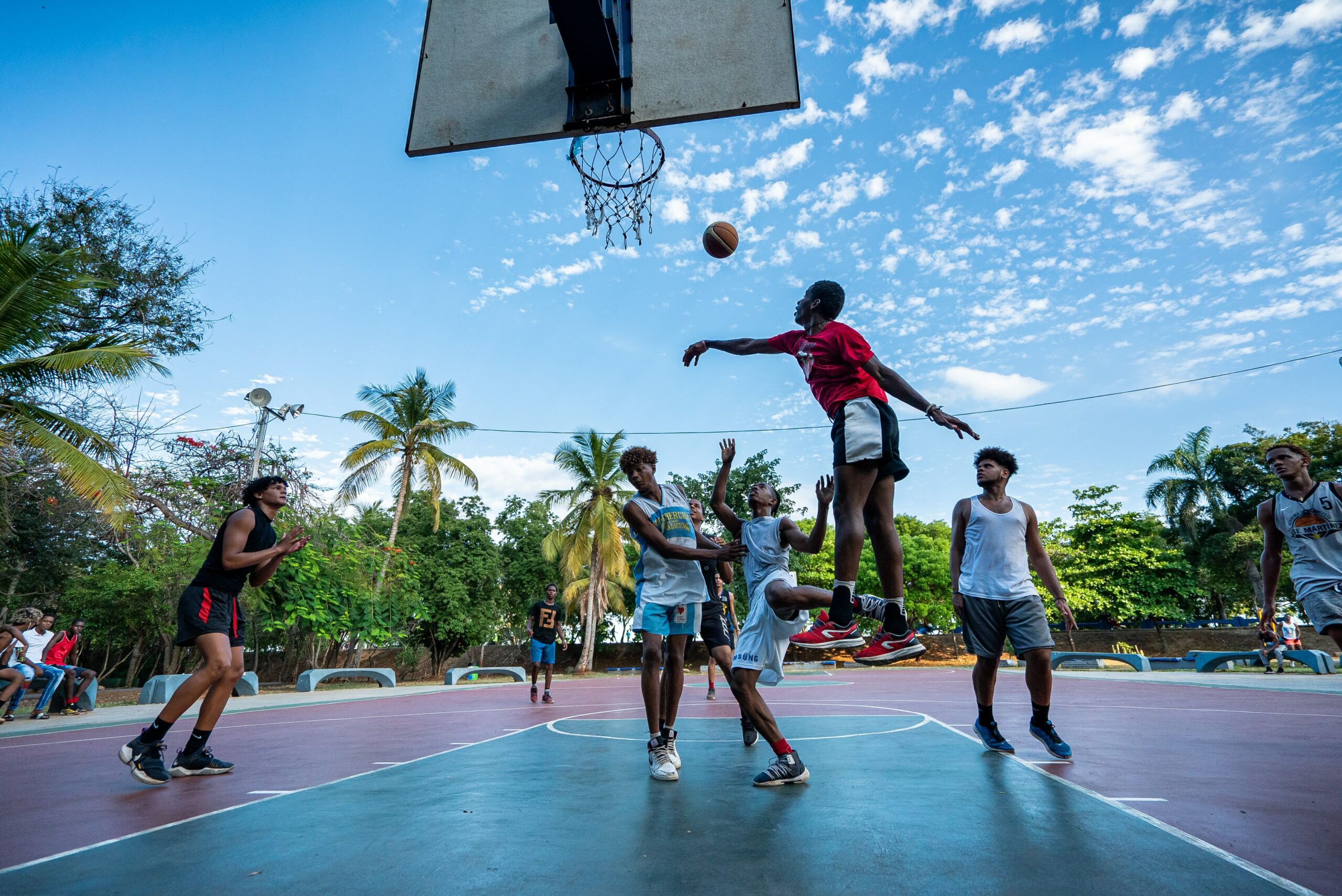 A group of kids playing basketball at a park. This is one of the most popular and inexpensive sports for kids to play.