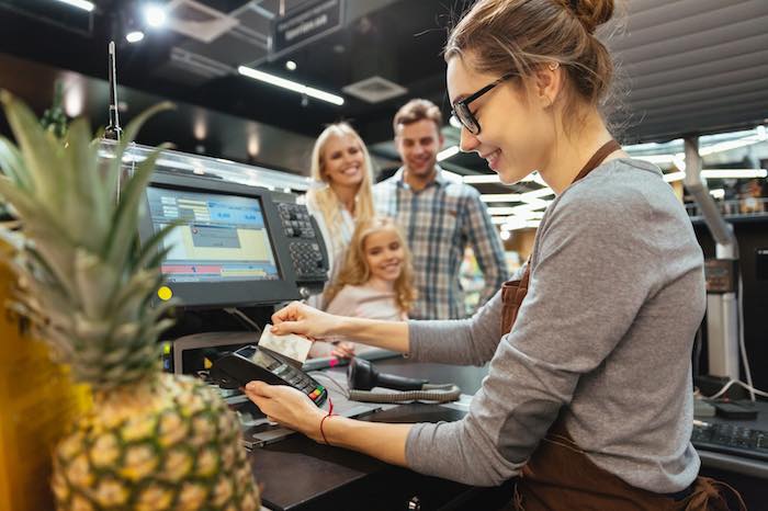 A teenaged girl working as a grocery store cashier.